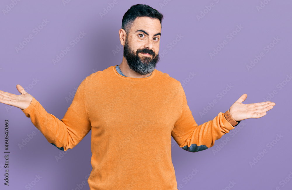 Hispanic man with beard wearing casual winter sweater smiling showing both hands open palms, presenting and advertising comparison and balance Hispanic man with beard wearing casual winter sweater smiling showing both hands open palms, presenting and advertising comparison and balance