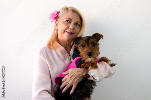 woman smiling looking forward holding a dog wearing pink outfit, dog in pink outfit, pink october