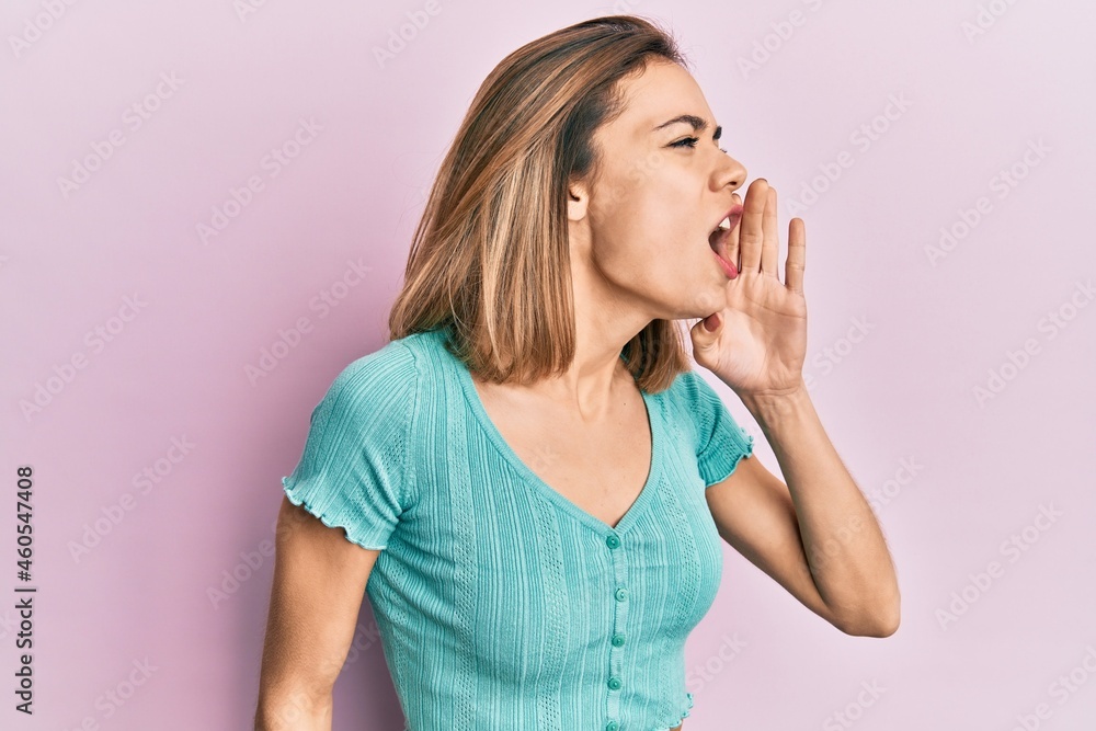 Young caucasian blonde woman wearing casual blue t shirt shouting and screaming loud to side with hand on mouth. communication concept. Young caucasian blonde woman wearing casual blue t shirt shouting and screaming loud to side with hand on mouth. communication concept.