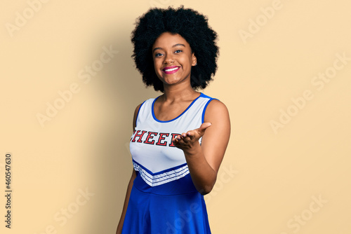 Young african american woman wearing cheerleader uniform smiling friendly offering handshake as greeting and welcoming. successful business.