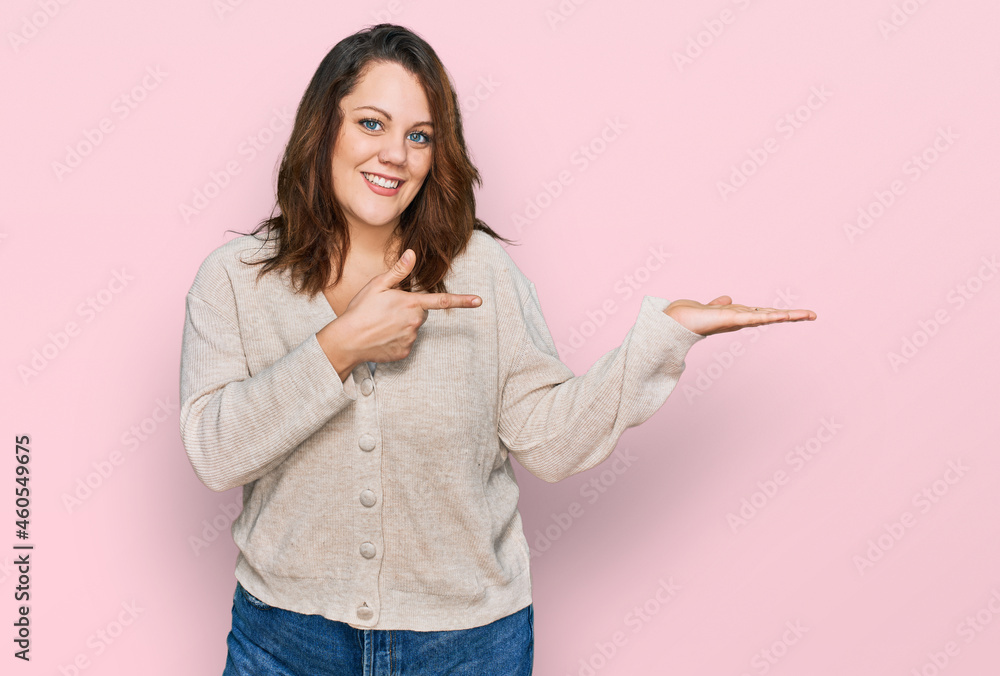 Young plus size woman wearing casual clothes amazed and smiling to the camera while presenting with hand and pointing with finger. Young plus size woman wearing casual clothes amazed and smiling to the camera while presenting with hand and pointing with finger.