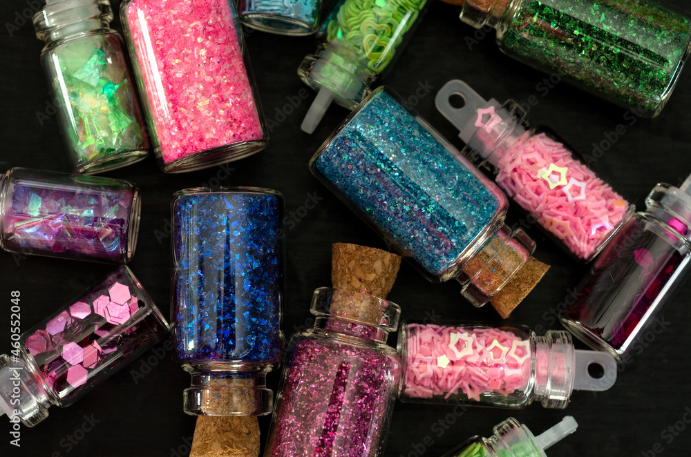 Fototapeta premium Macro Image of Mini Bottles with Sparkles,Hearts and Stars on Black Background