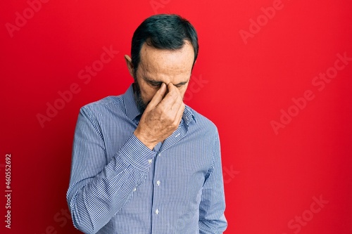 Middle age hispanic man wearing casual clothes tired rubbing nose and eyes feeling fatigue and headache. stress and frustration concept.