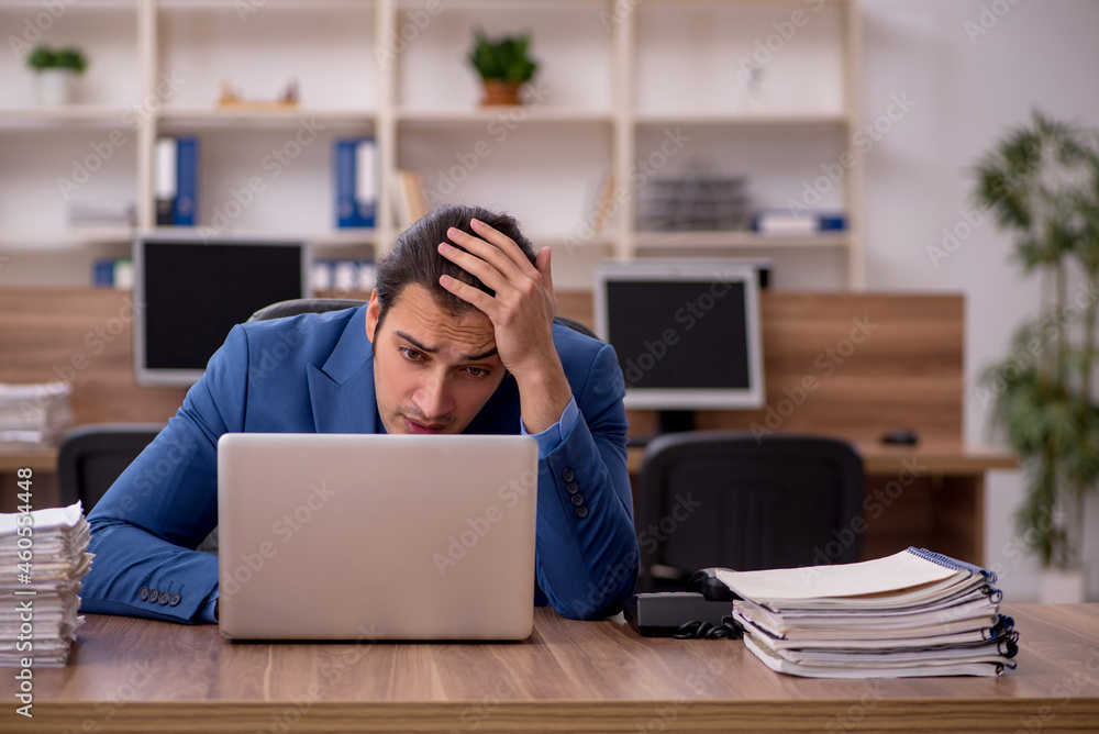 Young male employee and a lot of work in the office Young male employee and a lot of work in the office