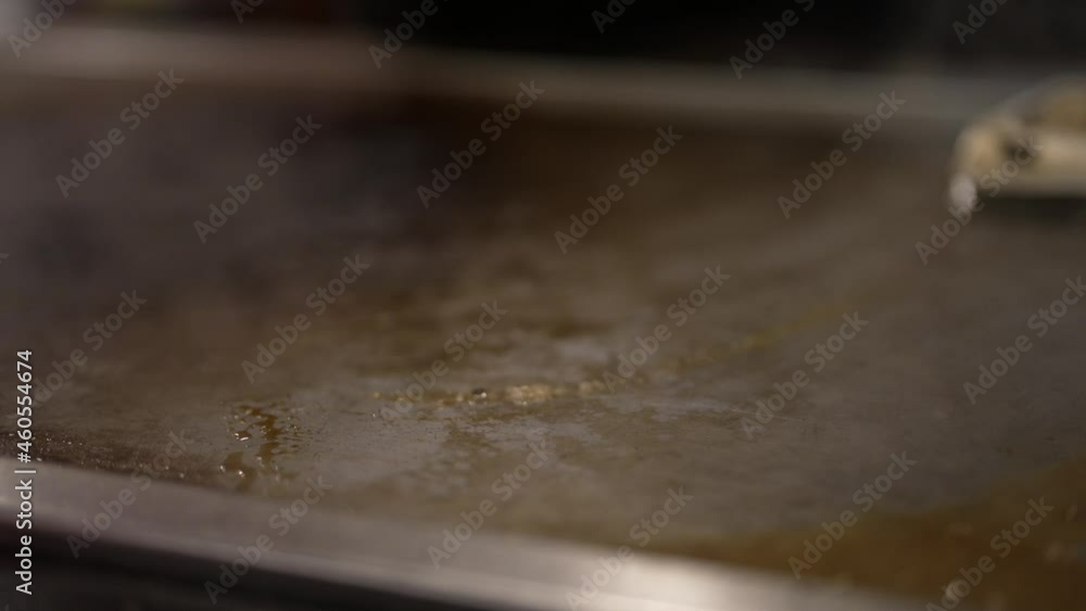This close up video shows a hot and steamy hibachi grill being cleaned with a tool. This close up video shows a hot and steamy hibachi grill being cleaned with a tool.