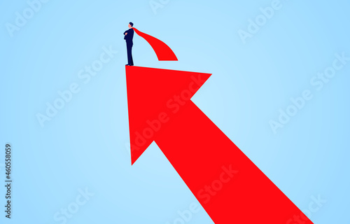 Successful businessman wearing red cape standing on upward growing red arrow.