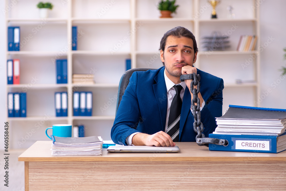 Chained male employee unhappy with excessive work in the ofiice Chained male employee unhappy with excessive work in the ofiice