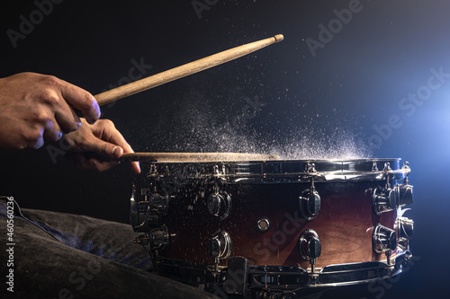 Photography A man plays with drumsticks on a snare drum with splashing water.