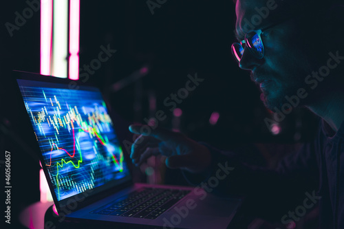 A man analyzing stock market charts, financial data on an electronic board.