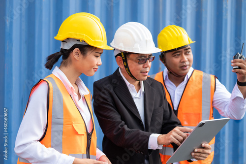 Selective focus at face Asian men worker. industrial warehouse container worker wearing safety workwear and taking with their supervisor while record data online with digital connection tablet.