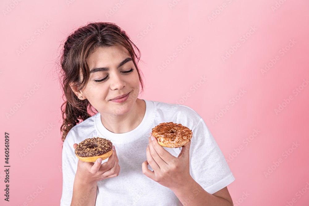 Portrait of a pretty, young woman showing donuts isolated over pink background. Portrait of a pretty, young woman showing donuts isolated over pink background.