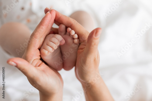 closeup of the bare feet of a newborn baby in his mother's hands on a white background. top view. caring for a newborn. mother's love. space for text. High quality photo © КРИСТИНА Игумнова