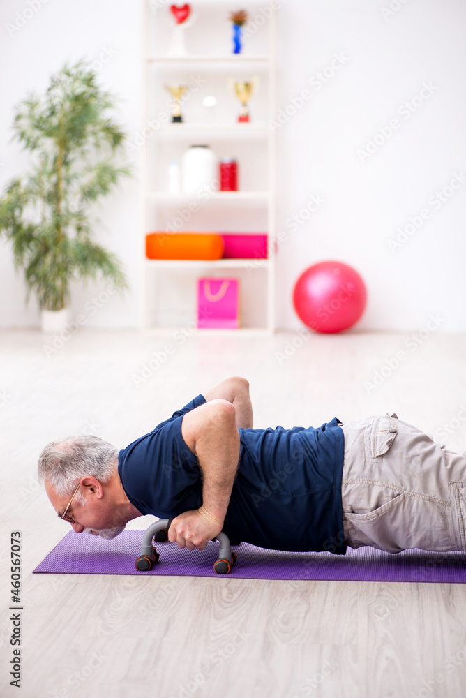 Old man doing sport exercises indoors Old man doing sport exercises indoors