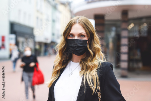 Portrait of young beautiful woman wearing medical mask as protection against corona virus. Covid pandemic time in Europe and in the world. Safety for people. Woman in summer city.
