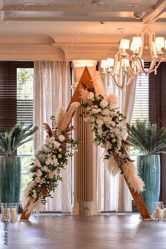 Triangular wooden arch with composition of pampasian grass, dianthus and roses. photo