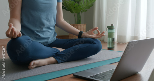 Close-up asia people woman enjoy study happy watch live video sit on sport mat at cozy home floor indoor easy zen class. Body calm life stress relax asana lotus pose in laptop self learn online media.