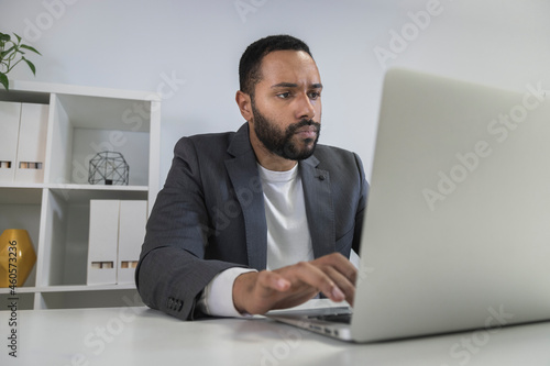 Young african american businessman working on laptop in home office. Focused entrepreneur typing on his computer.