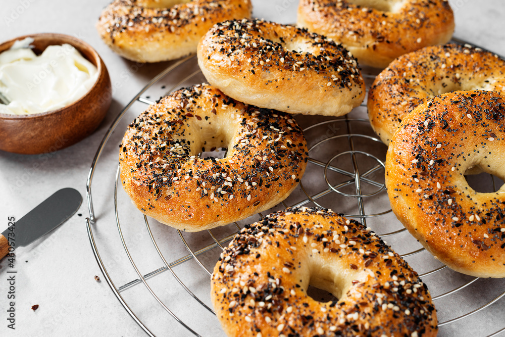 Fresh baked sourdough New York style bagels with cream cheese on light gray table. Fresh baked sourdough New York style bagels with cream cheese on light gray table.
