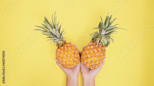 two pineapples in the palm isolated on a yellow background
