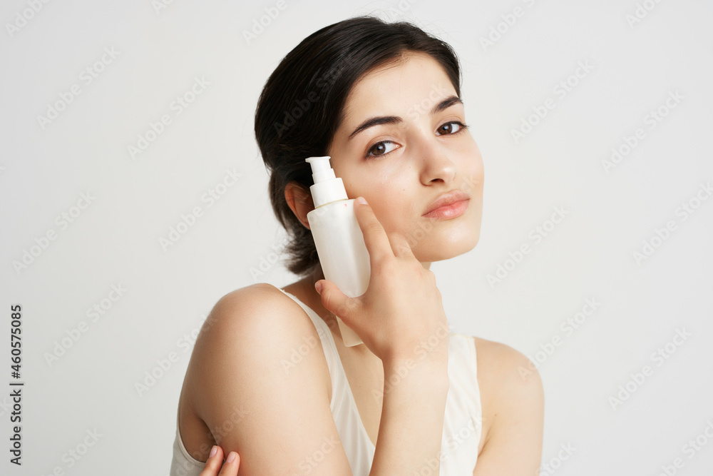 brunette holding near face lotion close-up clean skin brunette holding near face lotion close-up clean skin