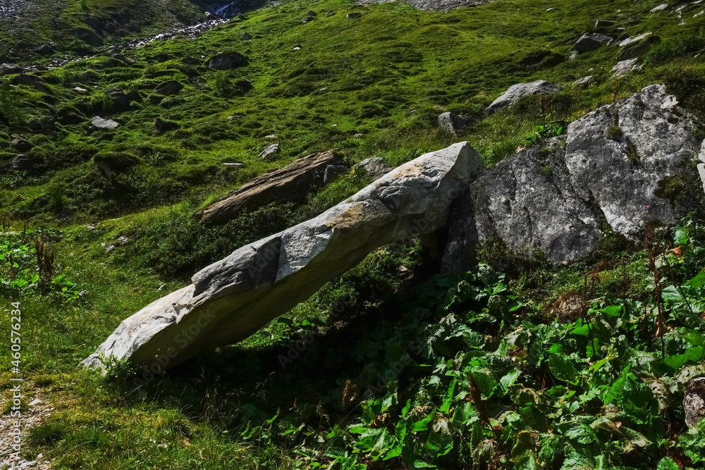 huge oblique lying rock on a green meadow while hiking