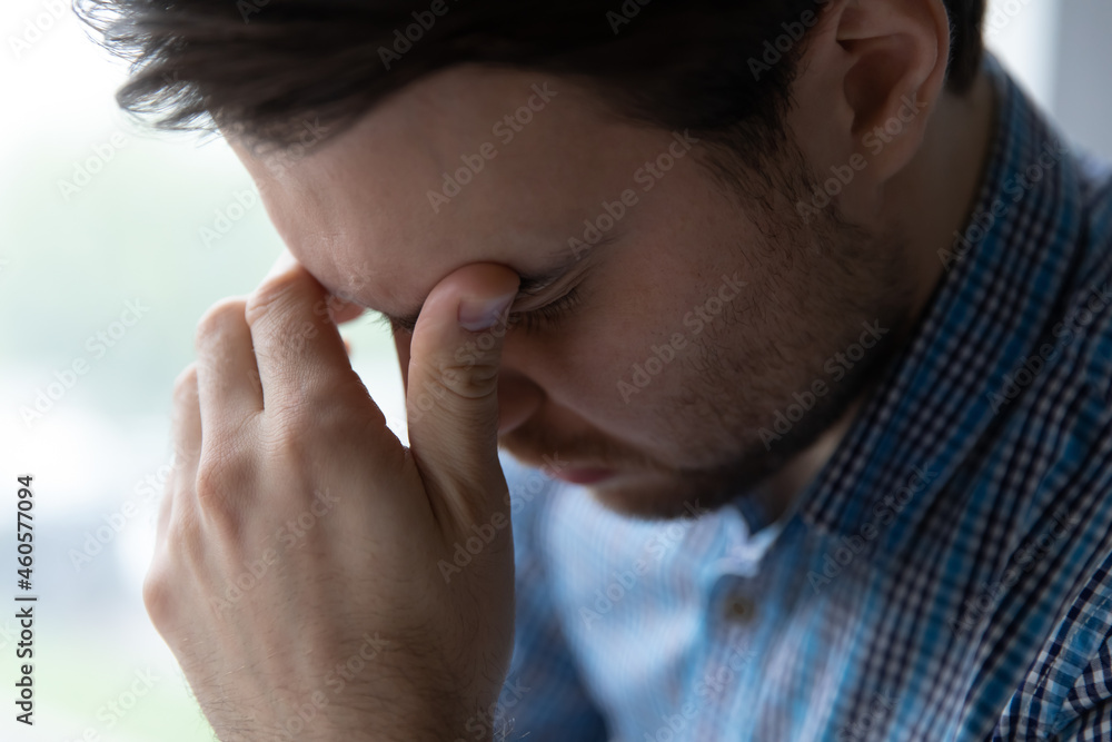 Crop close up of frustrated young man touching forehead, suffering from strong headache, migraine, upset exhausted guy feeling depressed and tired, relieving pain, thinking about personal problems Crop close up of frustrated young man touching forehead, suffering from strong headache, migraine, upset exhausted guy feeling depressed and tired, relieving pain, thinking about personal problems