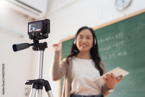 Selective focus, Smiling Asian Young woman teacher teaching and recording video with digital camera
