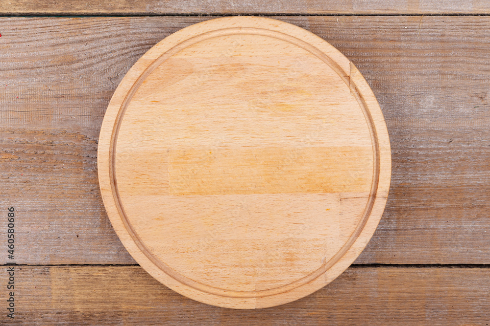 Empty cutting board in a round shape on a wooden background. Top view.