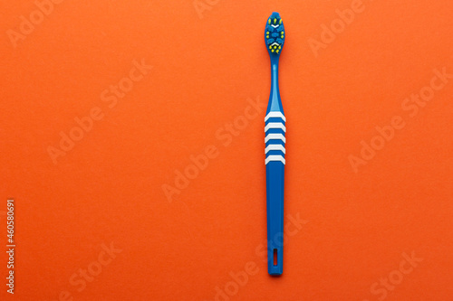 Toothbrush on orange background. Hygiene of the oral cavity. Top view.