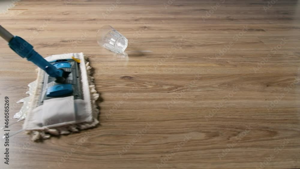 A spilled glass of milk on the laminate floor is cleaned with a mop close-up. A spilled glass of milk on the laminate floor is cleaned with a mop close-up.