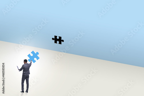 Businessman putting missing jigsaw puzzle piece