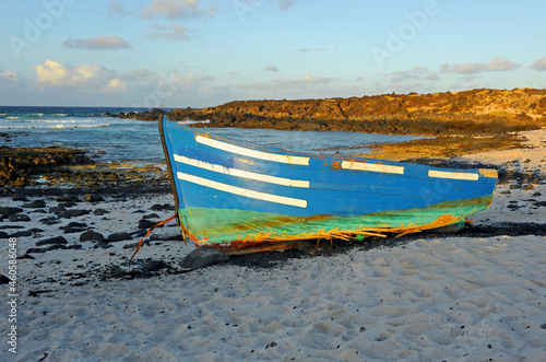 Patera abandonada en la costa de Lanzarote cerca de Orzola, inmigración ilegal desde África a las Islas Canarias, barca de madera naufragada en las playas de Lanzarote España photo
