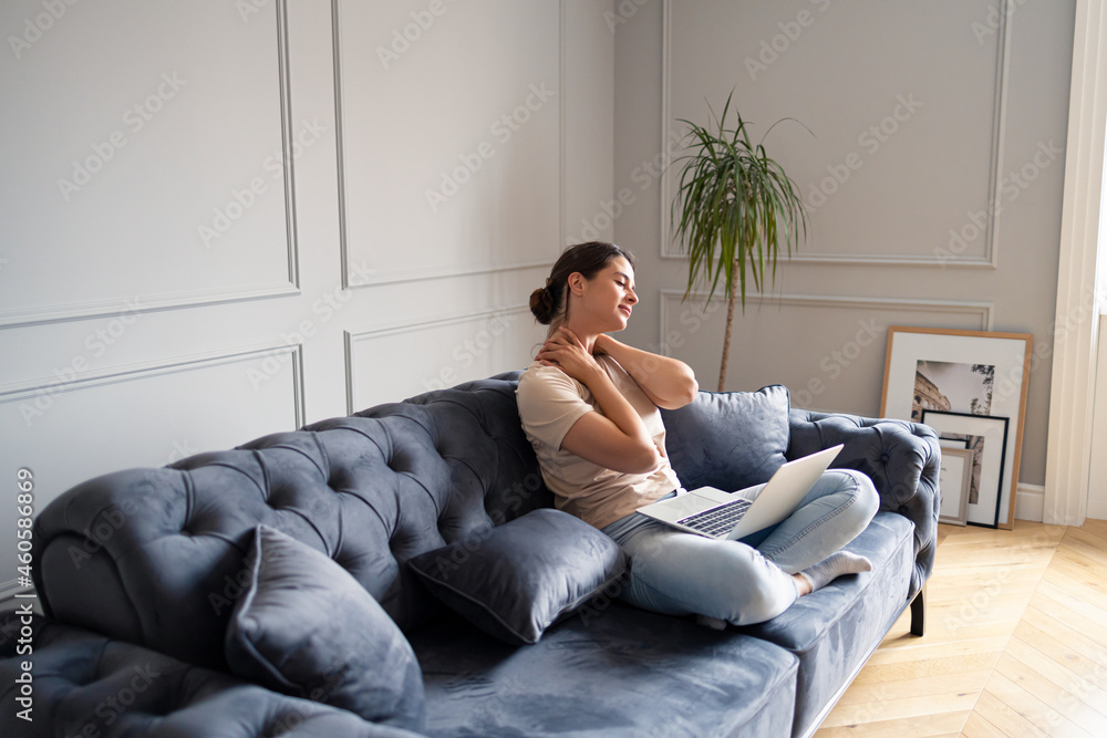 Overworked woman stretching her neck after working on laptop at home. Overworked woman stretching her neck after working on laptop at home.