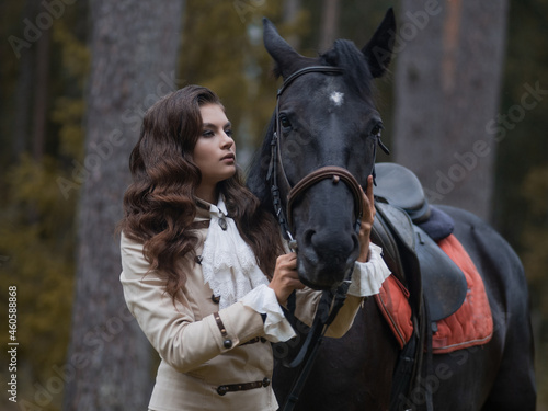 Portrait of a rider in a retro suit and her black horse.