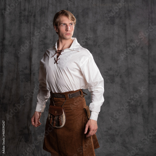 A young man in a leather kilt and a white lace-up blouse. A Scottish knight