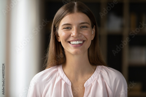 Happy beautiful young Caucasian woman with perfect white teeth looking at camera, laughing. Millennial teen student girl in casual female home head shot portrait. Dentistry, beauty care concept