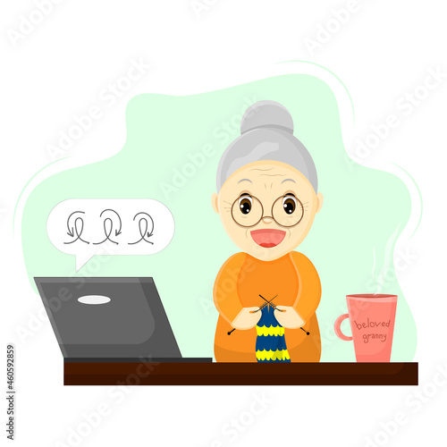 A happy grandmother at a table with a laptop is taking a knitting master class