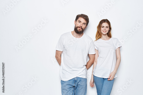 Cheerful man and woman in white t-shirts and jeans design studio light background