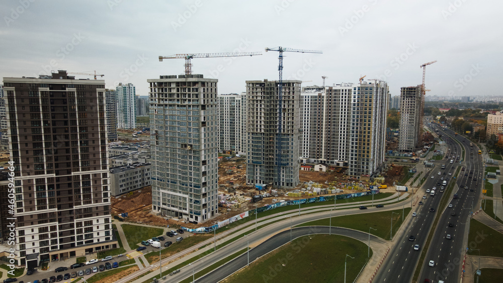 Construction of modern multi-storey buildings. Construction of a new city block. Buildings under construction and tower cranes. Aerial photography in cloudy weather.