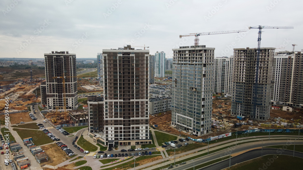 Construction of modern multi-storey buildings. Construction of a new city block. Buildings under construction and tower cranes. Aerial photography in cloudy weather. Construction of modern multi-storey buildings. Construction of a new city block. Buildings under construction and tower cranes. Aerial photography in cloudy weather.