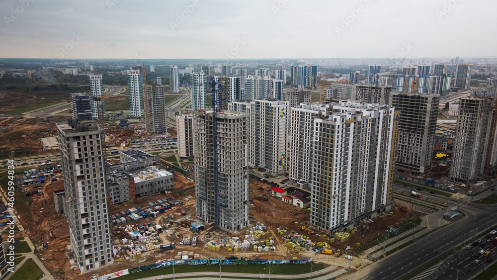 Obraz premium Construction of modern multi-storey buildings. Construction of a new city block. Buildings under construction and tower cranes. Aerial photography in cloudy weather.