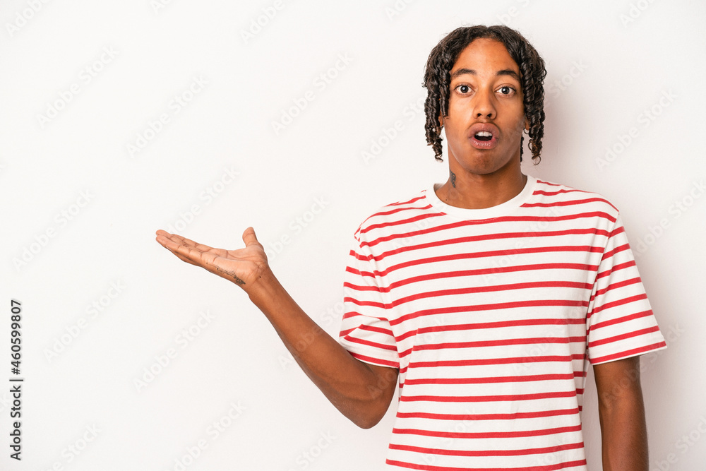 Young african american man isolated on white background impressed holding copy space on palm.