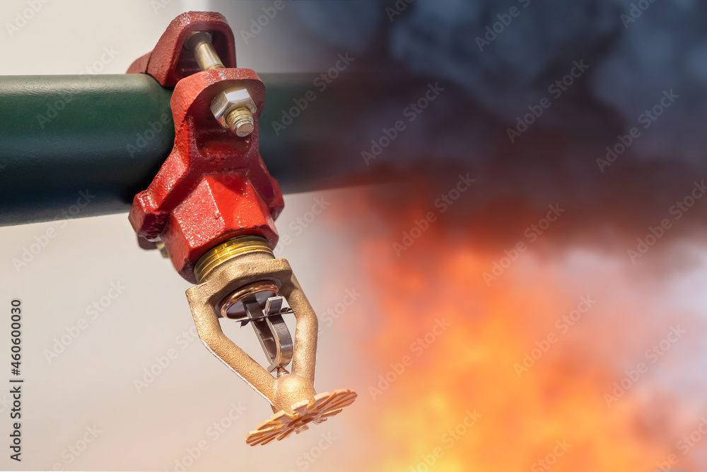 Sprinkler for fire extinguishing system. Sprinkler next to flame and smoke. Concept - equipment for fire fighting. Sprinkler for extinguishing flame in building. Internal fire extinguishing system. - obrazy, fototapety, plakaty 