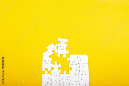 white jigsaw puzzle pieces isolated on a yellow background