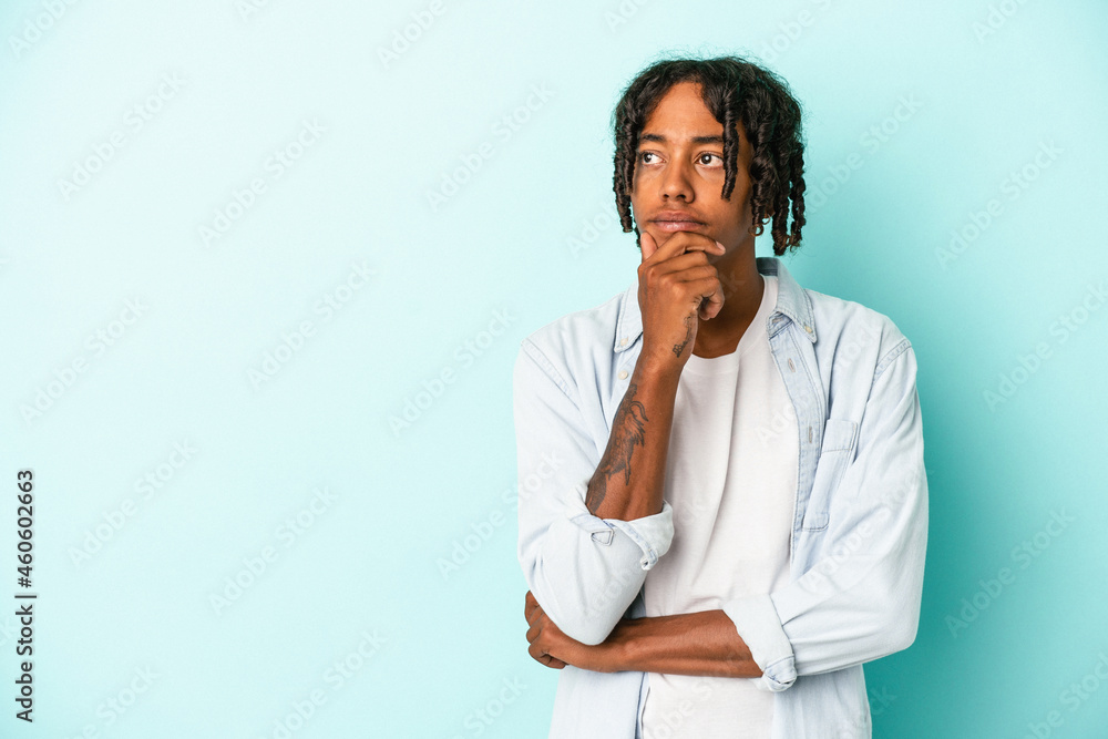 Young african american man isolated on blue background looking sideways with doubtful and skeptical expression. Young african american man isolated on blue background looking sideways with doubtful and skeptical expression.