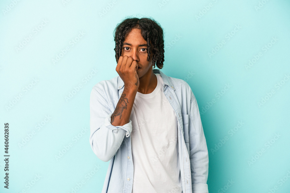 Young african american man isolated on blue background biting fingernails, nervous and very anxious. Young african american man isolated on blue background biting fingernails, nervous and very anxious.