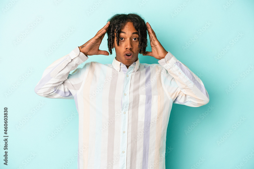 Young african american man isolated on blue background celebrating a victory or success, he is surprised and shocked. Young african american man isolated on blue background celebrating a victory or success, he is surprised and shocked.