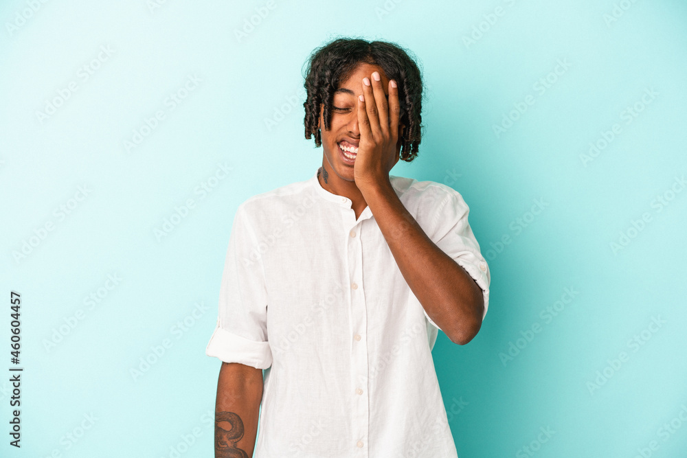 Young african american man isolated on blue background having fun covering half of face with palm. Young african american man isolated on blue background having fun covering half of face with palm.