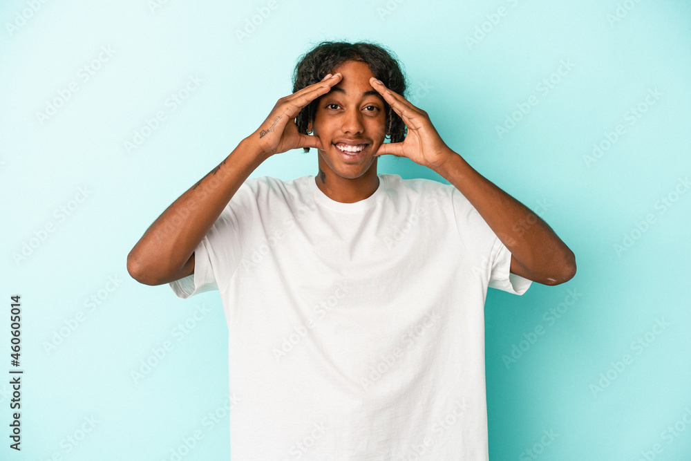 Young african american man isolated on blue background receiving a pleasant surprise, excited and raising hands. Young african american man isolated on blue background receiving a pleasant surprise, excited and raising hands.