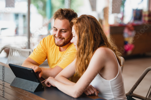 A coung couple friends or colleague sitting in cafe and looking to a tablet.